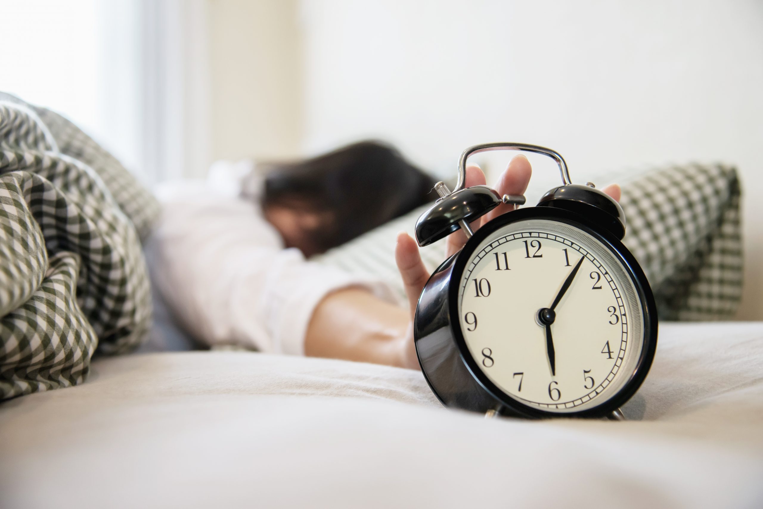 sleepy-woman-reaching-holding-the-alarm-clock Mujer_durmiendo